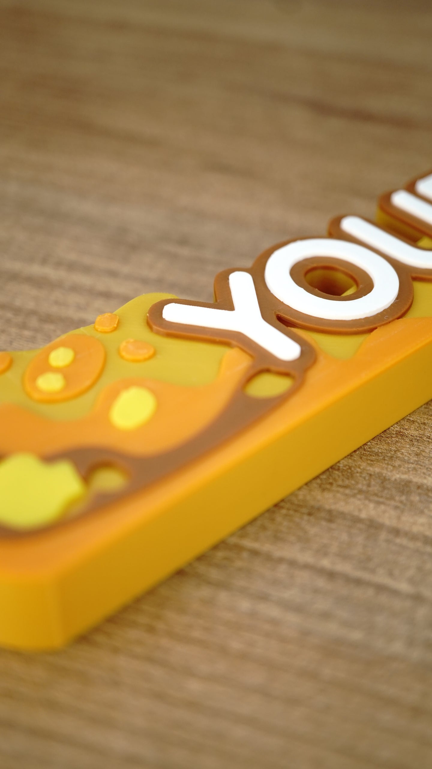 Macro view of the raised lettering and layered amber artwork on a personalized Palia Royal Amber gaming desk name sign.