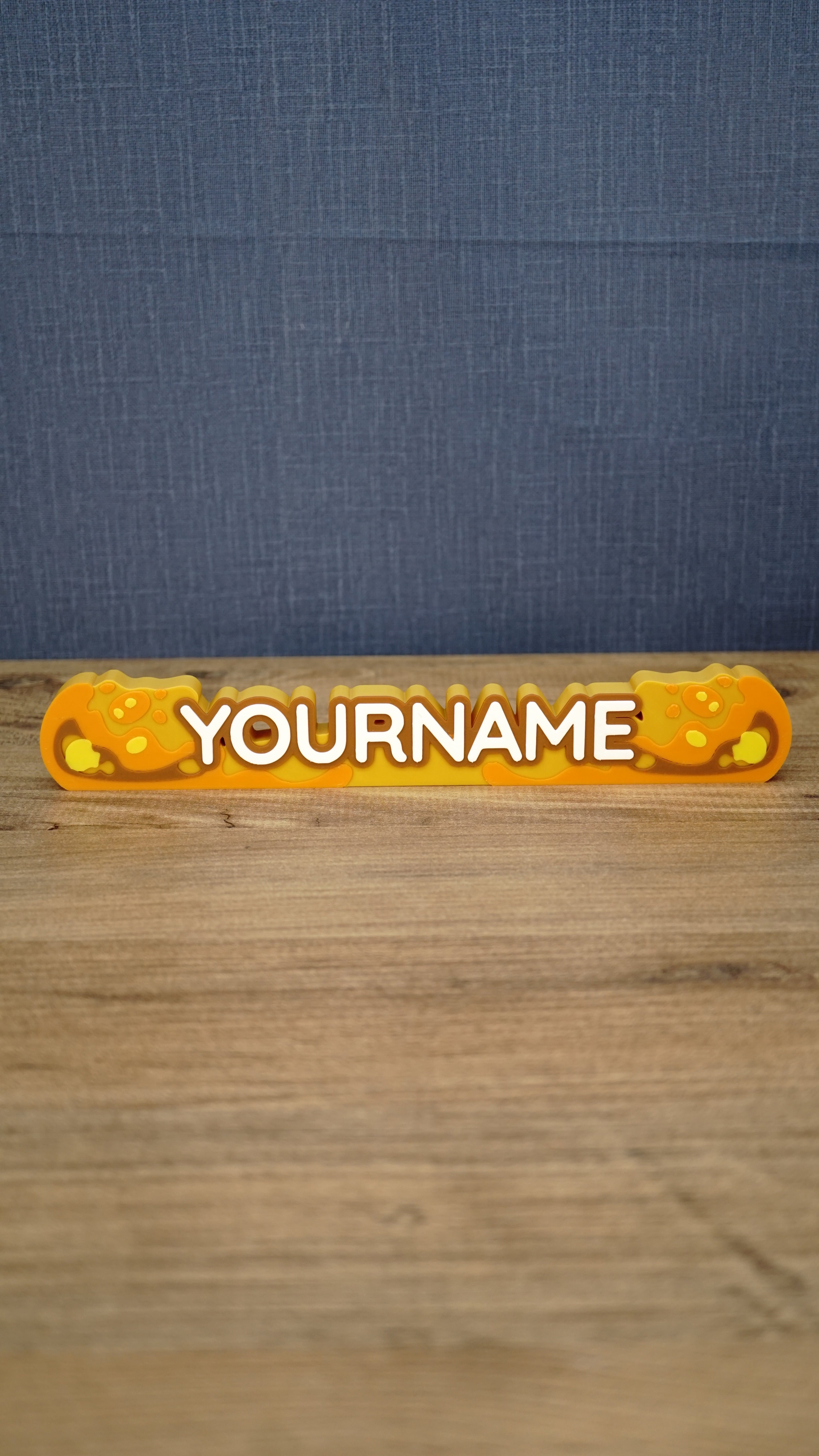 Front view of a personalized Palia Royal Amber nameplate with bold white lettering, orange and gold amber details, displayed on a wooden gaming desk.