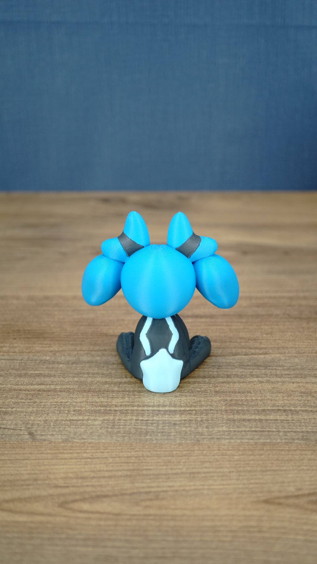 Back view of the Royal Sernuk plush figure from Palia showing the blue head, gray body, and light blue tail detail.