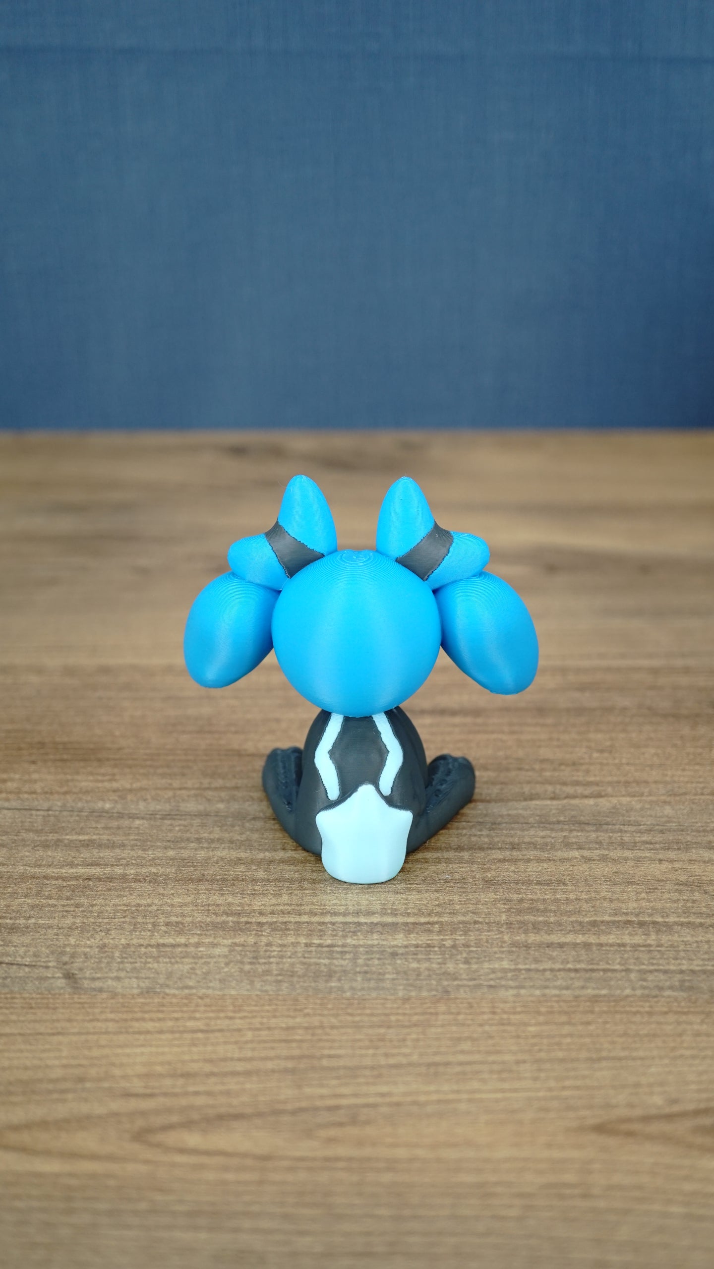 Back view of the Royal Sernuk plush figure from Palia showing the blue head, gray body, and light blue tail detail.