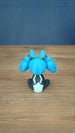 Back view of the Royal Sernuk plush figure from Palia showing the blue head, gray body, and light blue tail detail.