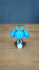 Back view of the Royal Sernuk plush figure from Palia showing the blue head, gray body, and light blue tail detail.