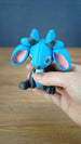 Close-up of the Royal Sernuk plush figure from Palia highlighting its blue face, pink ears, gray body, and horn details.