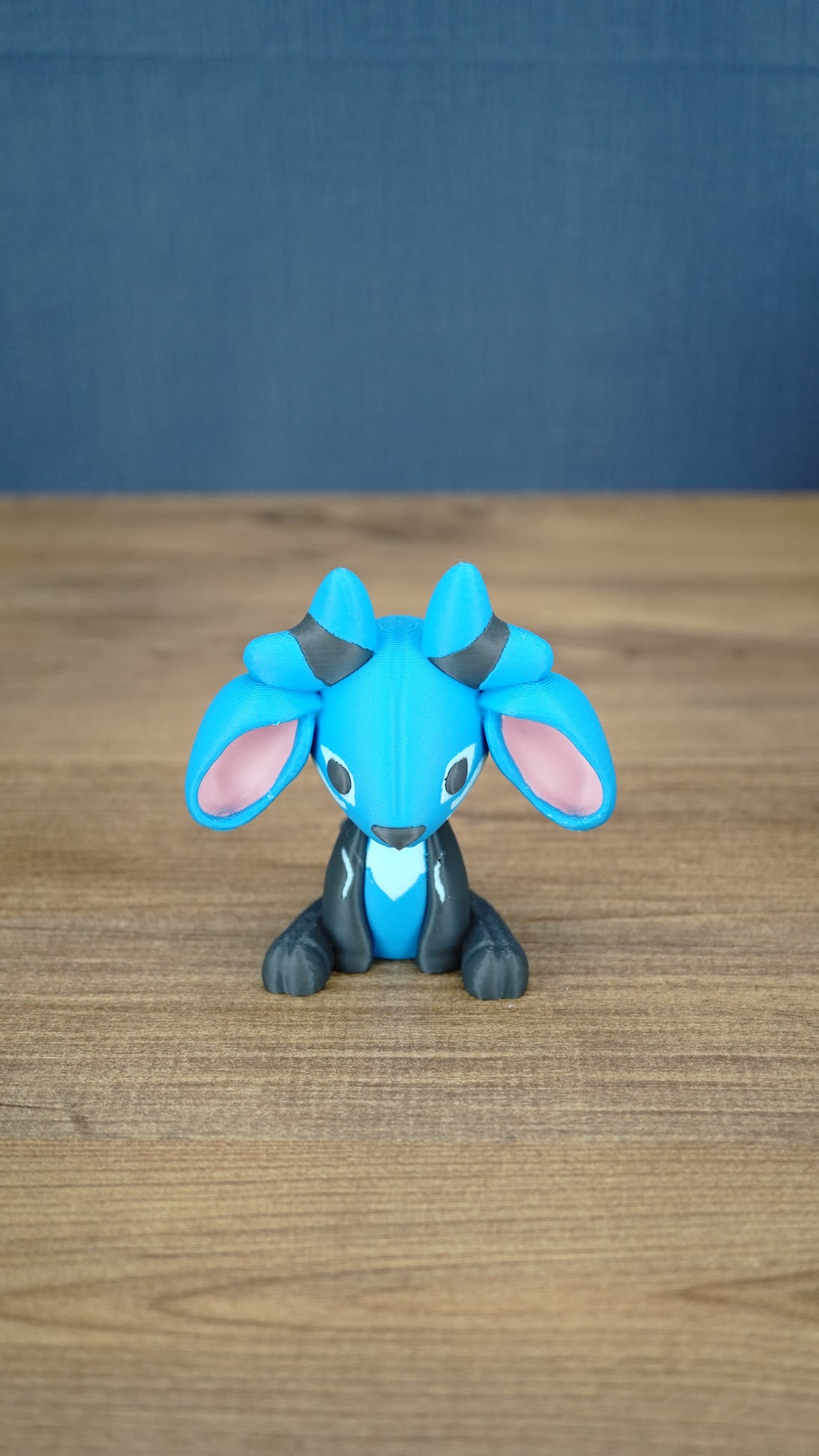 Royal Sernuk plush figure from Palia shown from the front with blue head, gray body, pink ears, and blue horns.