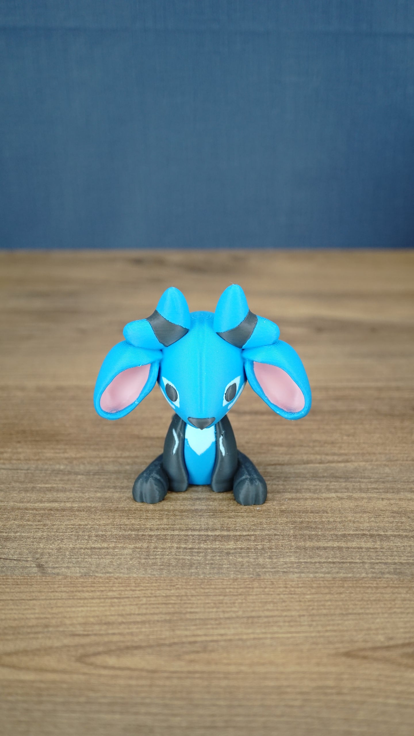 Royal Sernuk plush figure from Palia shown from the front with blue head, gray body, pink ears, and blue horns.