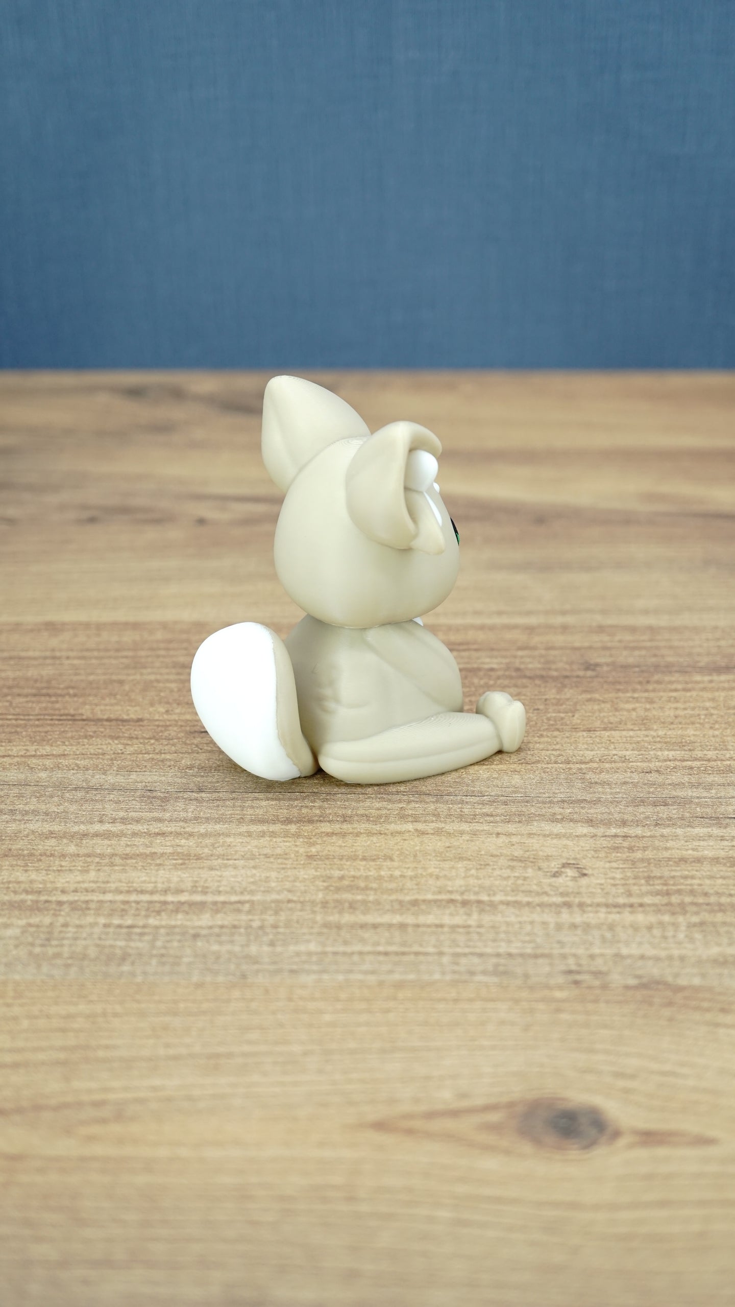 Back side view of a 3D printed Sandi the Palcat plush figure showing its curled tail with white tip, seated pose, and large ears.