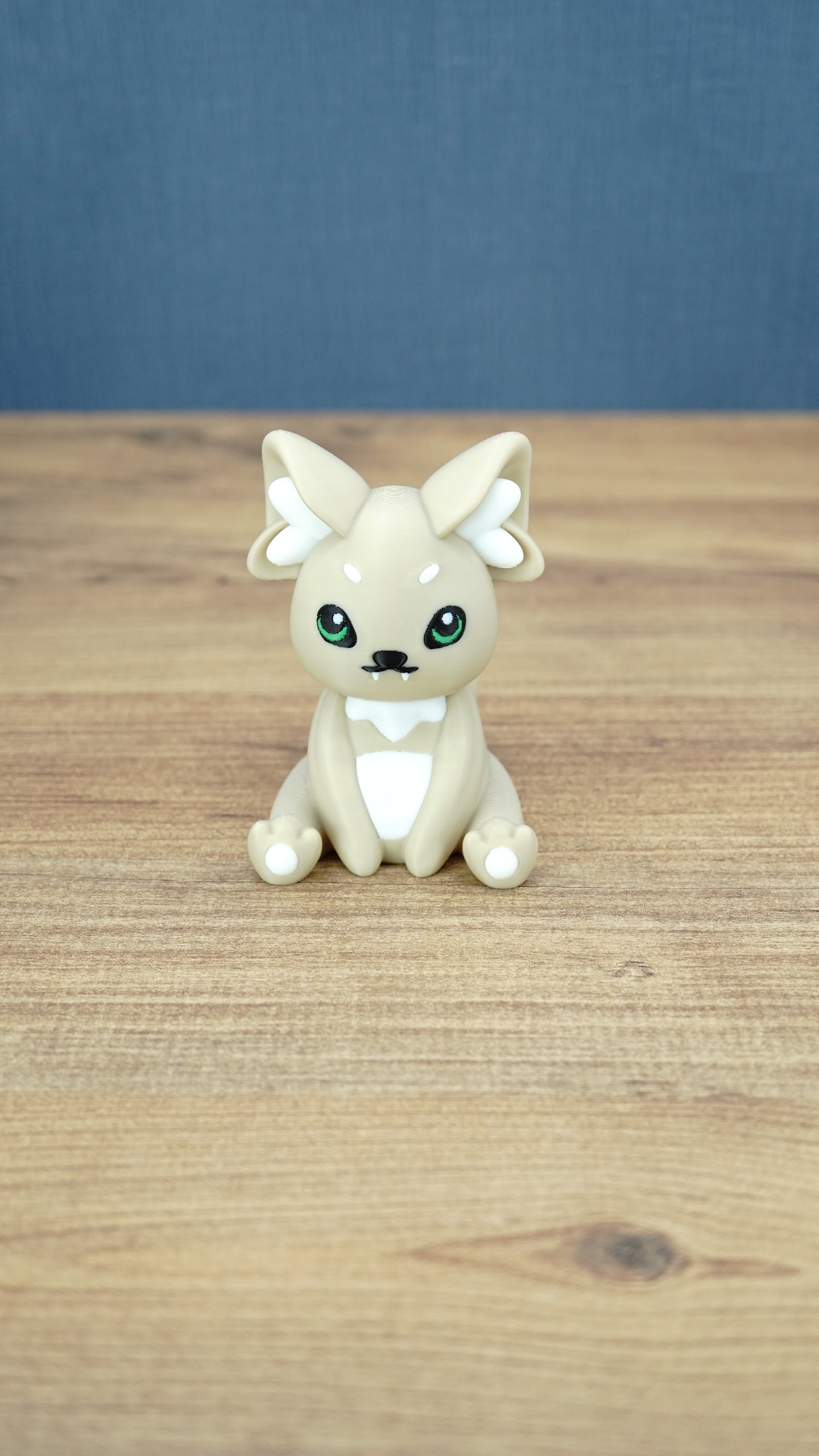 Front view of a 3D printed Sandi the Palcat plush figure with sandy beige fur, white chest and ear details, green eyes, and tiny white fangs.