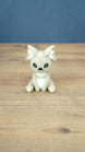 Front view of a 3D printed Sandi the Palcat plush figure with sandy beige fur, white chest and ear details, green eyes, and tiny white fangs.