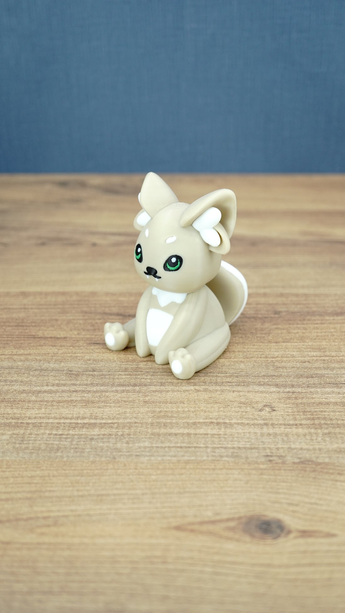 Side view of a 3D printed Sandi the Palcat plush figure showing its curled tail, large pointed ears, white accents, and green eyes.