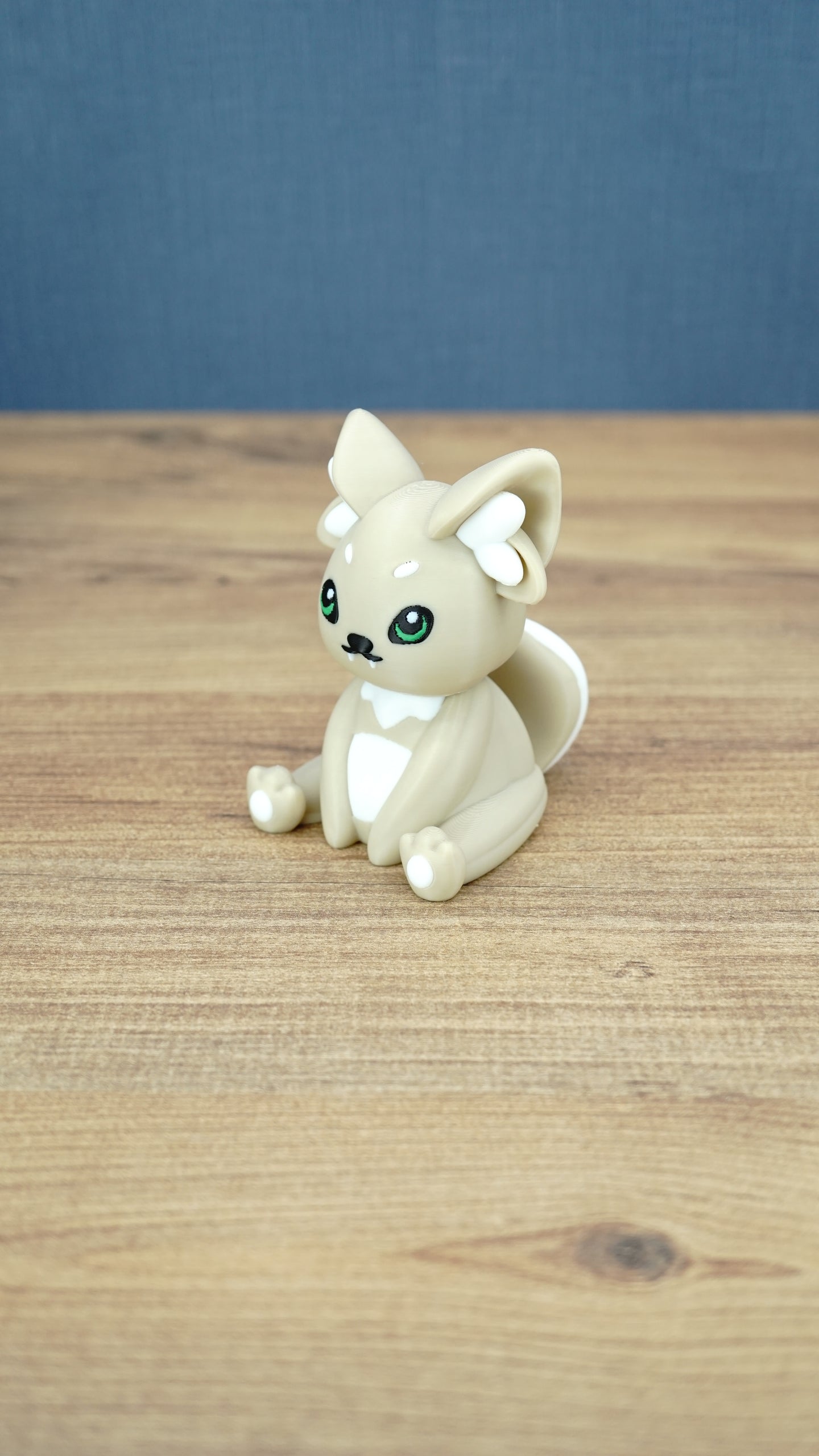 Side view of a 3D printed Sandi the Palcat plush figure showing its curled tail, large pointed ears, white accents, and green eyes.