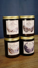 Four Palia scented candles stacked in amber glass jars with gold lids, featuring Royal Highlands, Kilima Valley, Bahari Bay and Elderwood.