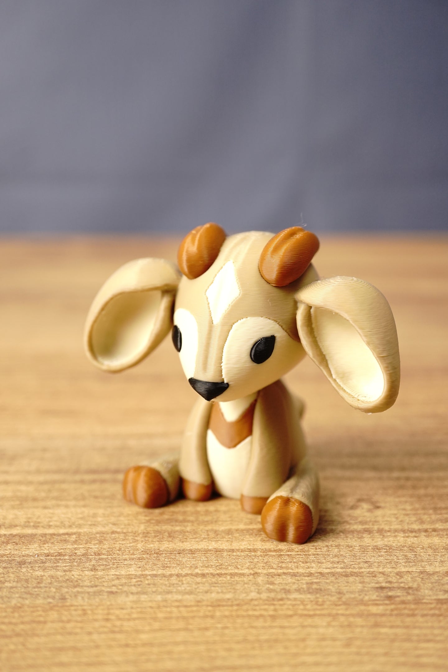 Close angled view of a Palia Sernuk figure by Created by Lou with tan colouring, brown horns, wide ears and a cute seated design.