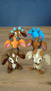 Group of 3D printed Palia sernuk plush figures arranged together on a wooden tabletop, showing multiple color variants including Royal, Elder, Golden, and other sernuk styles.