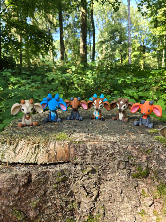 Six colourful 3D printed Palia Sernuk plush figures displayed in a row on a mossy tree stump in a forest.