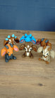 Overhead view of a collection of Palia sernuk plush figures in multiple color variants arranged in a circle on a wooden tabletop.