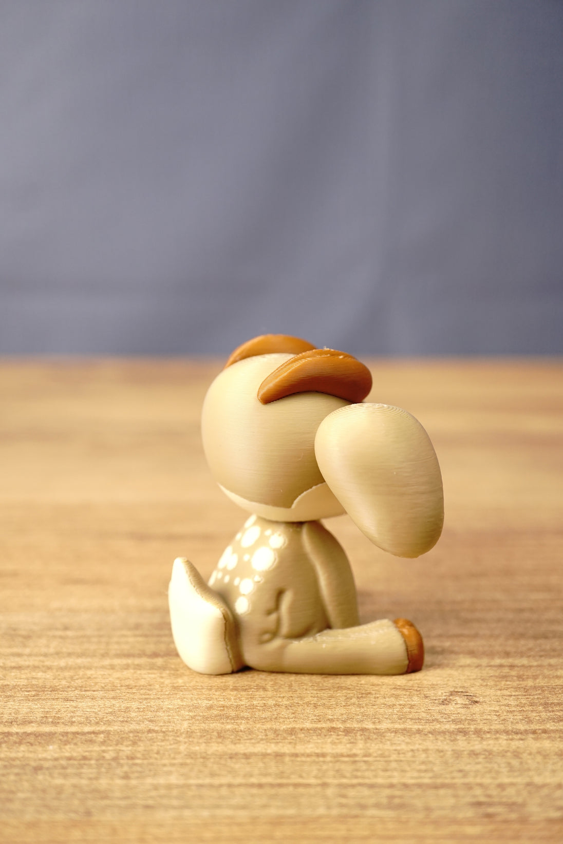 Rear side view of a Sernuk Plush figure by Created by Lou showing its curved tail, large ear and decorative white back spots.