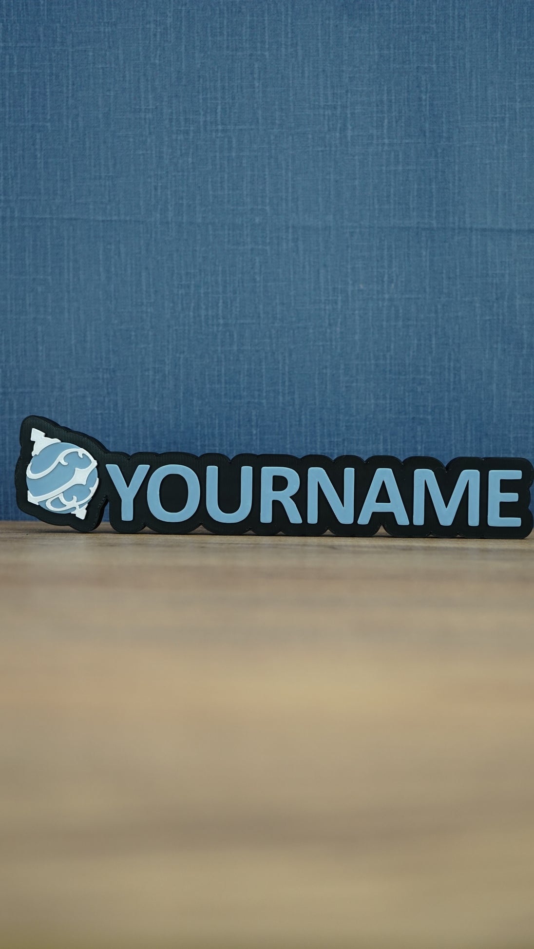 Front view of a light blue and white Palworld Sphere personalised nameplate on a black base, with bold YOURNAME lettering for desk or shelf display.