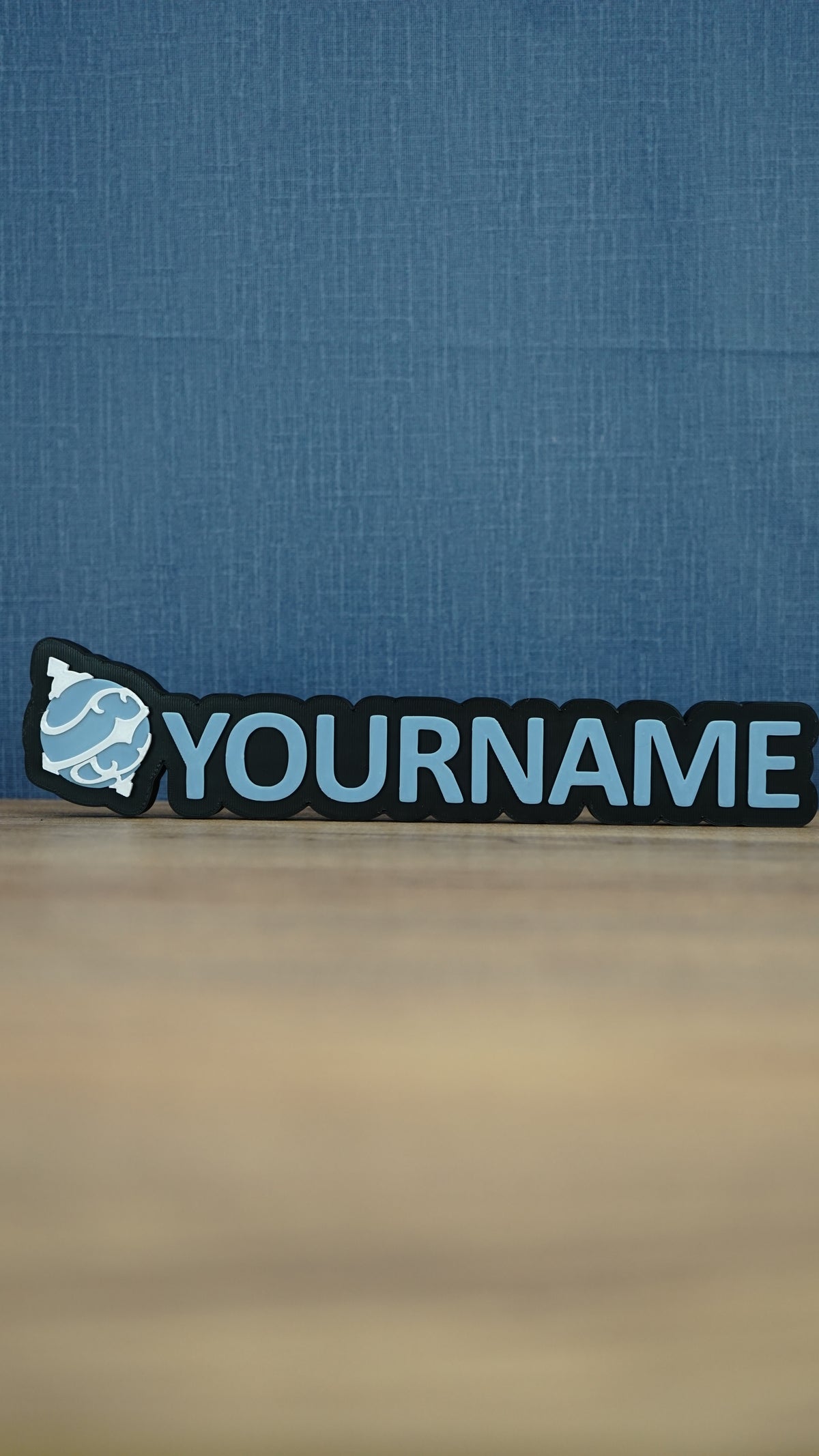Front view of a light blue and white Palworld Sphere personalised nameplate on a black base, with bold YOURNAME lettering for desk or shelf display.