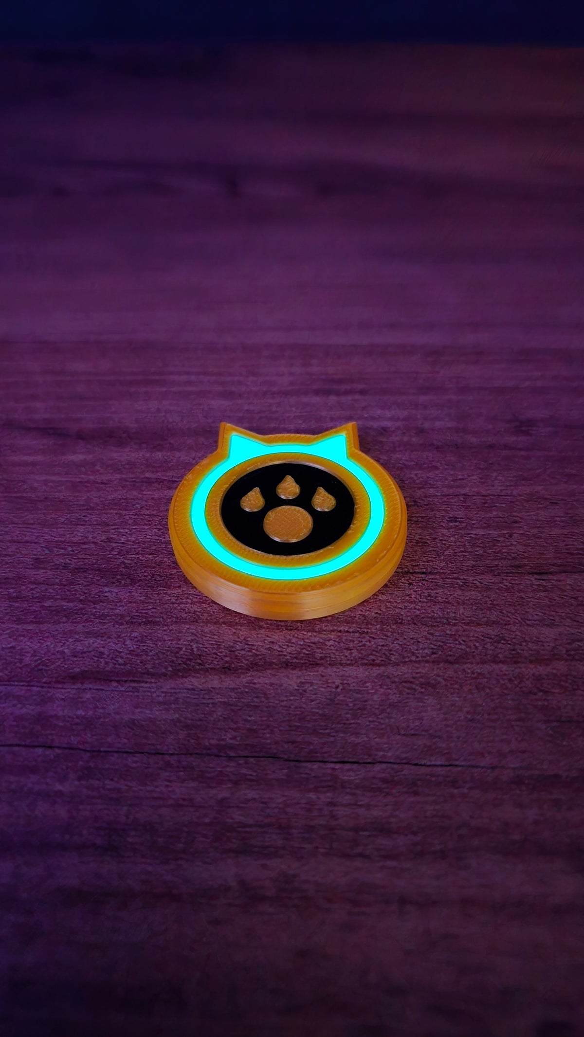 Single glow-in-the-dark Palworld-inspired dog coin replica with a turquoise glowing ring and paw-print design on a dark tabletop.