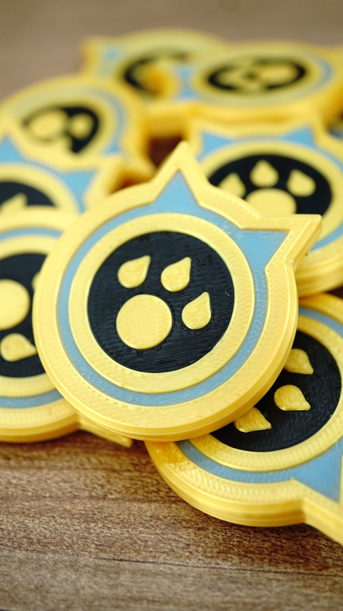 Close-up of a Palworld Dog Coin replica resting on other tokens, highlighting the raised paw emblem, yellow border and light blue detail.