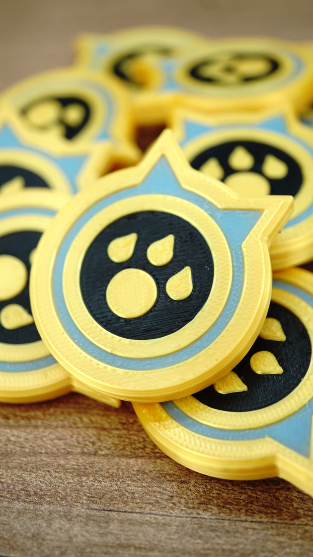 Close-up of a Palworld Dog Coin replica resting on other tokens, highlighting the raised paw emblem, yellow border and light blue detail.
