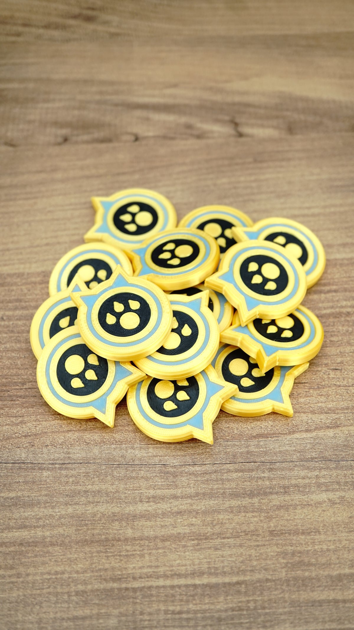 Pile of Palworld Dog Coin replica tokens on a wooden surface, showing multiple yellow, light blue and black collectible coins together.
