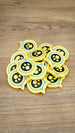 Pile of Palworld Dog Coin replica tokens on a wooden surface, showing multiple yellow, light blue and black collectible coins together.