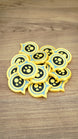 Pile of Palworld Dog Coin replica tokens on a wooden surface, showing multiple yellow, light blue and black collectible coins together.
