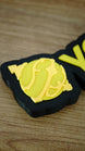Close-up of the yellow Sphere emblem on a personalised Palworld nameplate, showing the layered decorative detail beside matching yellow lettering.