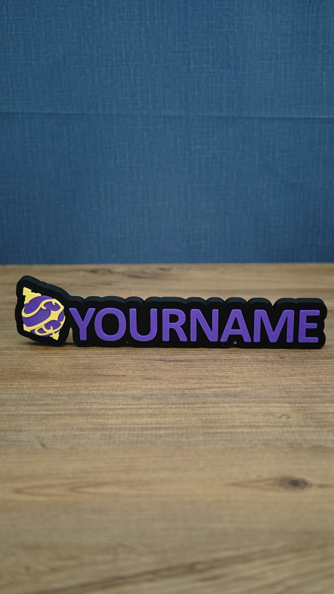 Personalised Palworld Sphere nameplate in purple and yellow on a black base, shown front-on with raised custom YOURNAME lettering for a gaming setup.