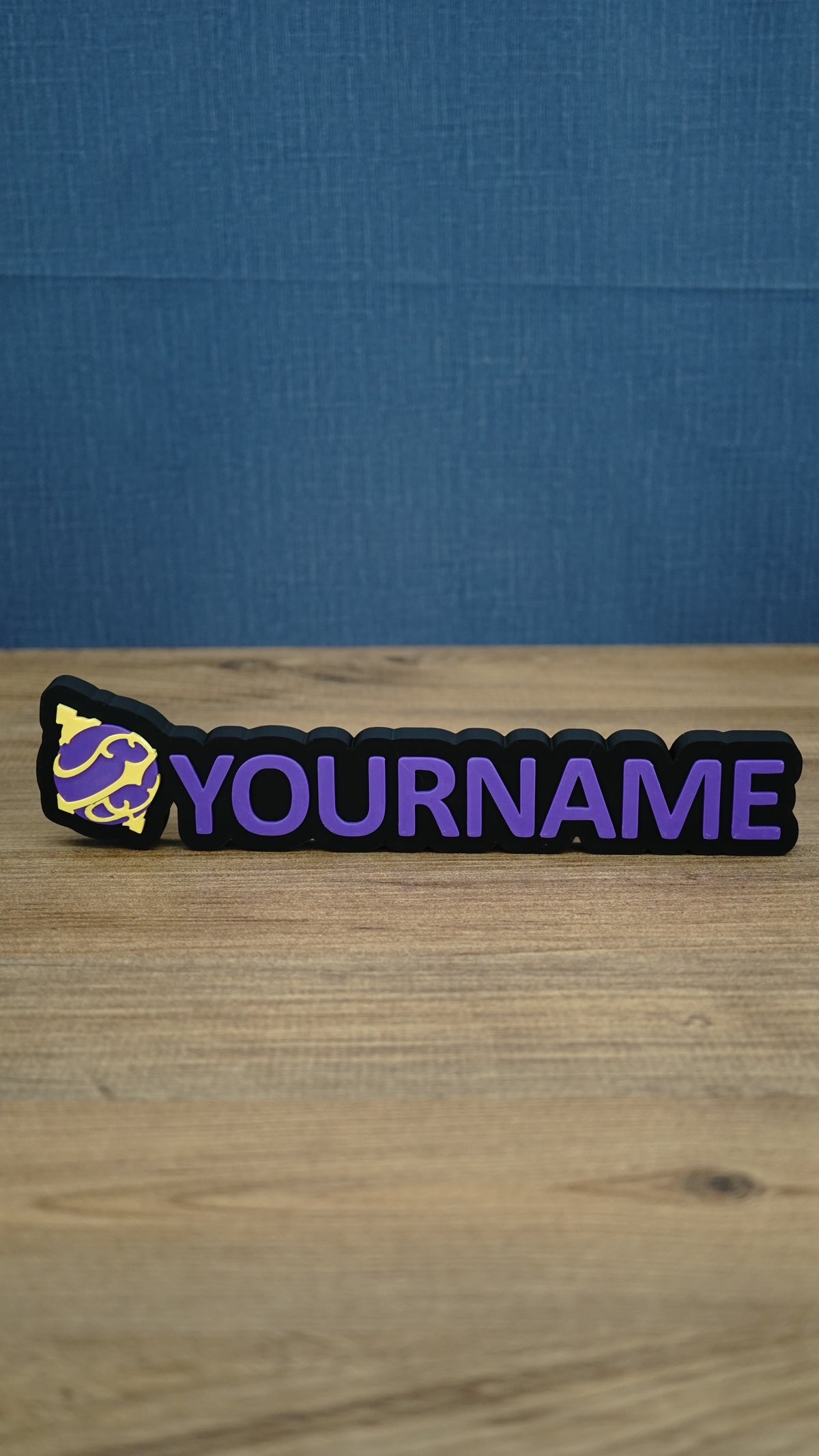 Personalised Palworld Sphere nameplate in purple and yellow on a black base, shown front-on with raised custom YOURNAME lettering for a gaming setup.