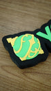 Close-up of the green and yellow Sphere emblem on a personalised Palworld nameplate, with bright green lettering and a black display base.