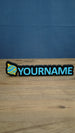 Personalised Palworld Sphere nameplate in blue and yellow on a black base, displayed front-on with custom YOURNAME lettering on a wooden desk.