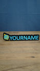 Personalised Palworld Sphere nameplate in blue and yellow on a black base, displayed front-on with custom YOURNAME lettering on a wooden desk.