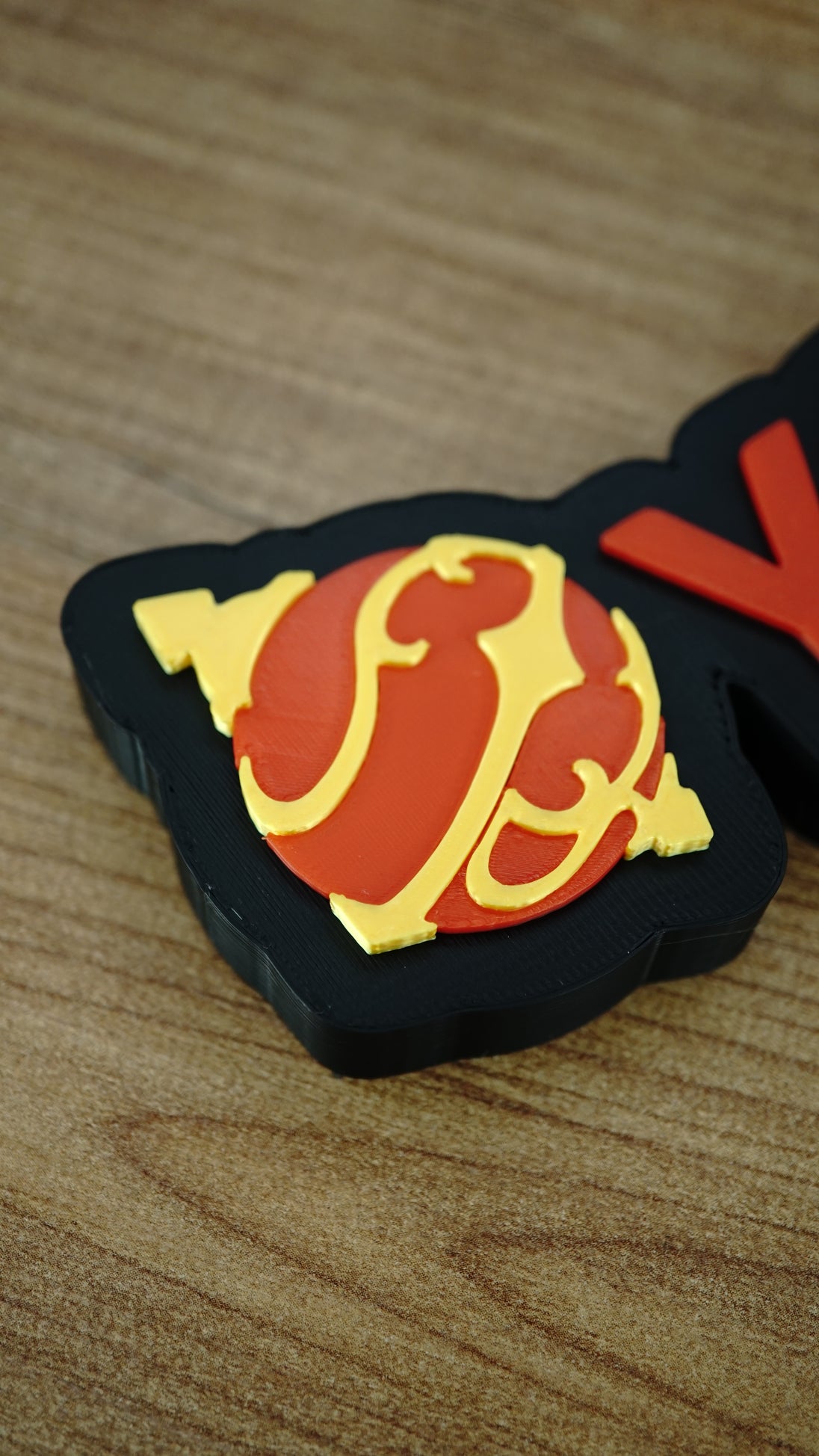 Close-up of the orange and yellow Sphere emblem on a personalised Palworld nameplate, paired with orange lettering on a black display base.
