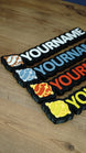 Angled group display of several personalised Palworld Sphere nameplates in white, blue, red and yellow colourways on a wooden tabletop.