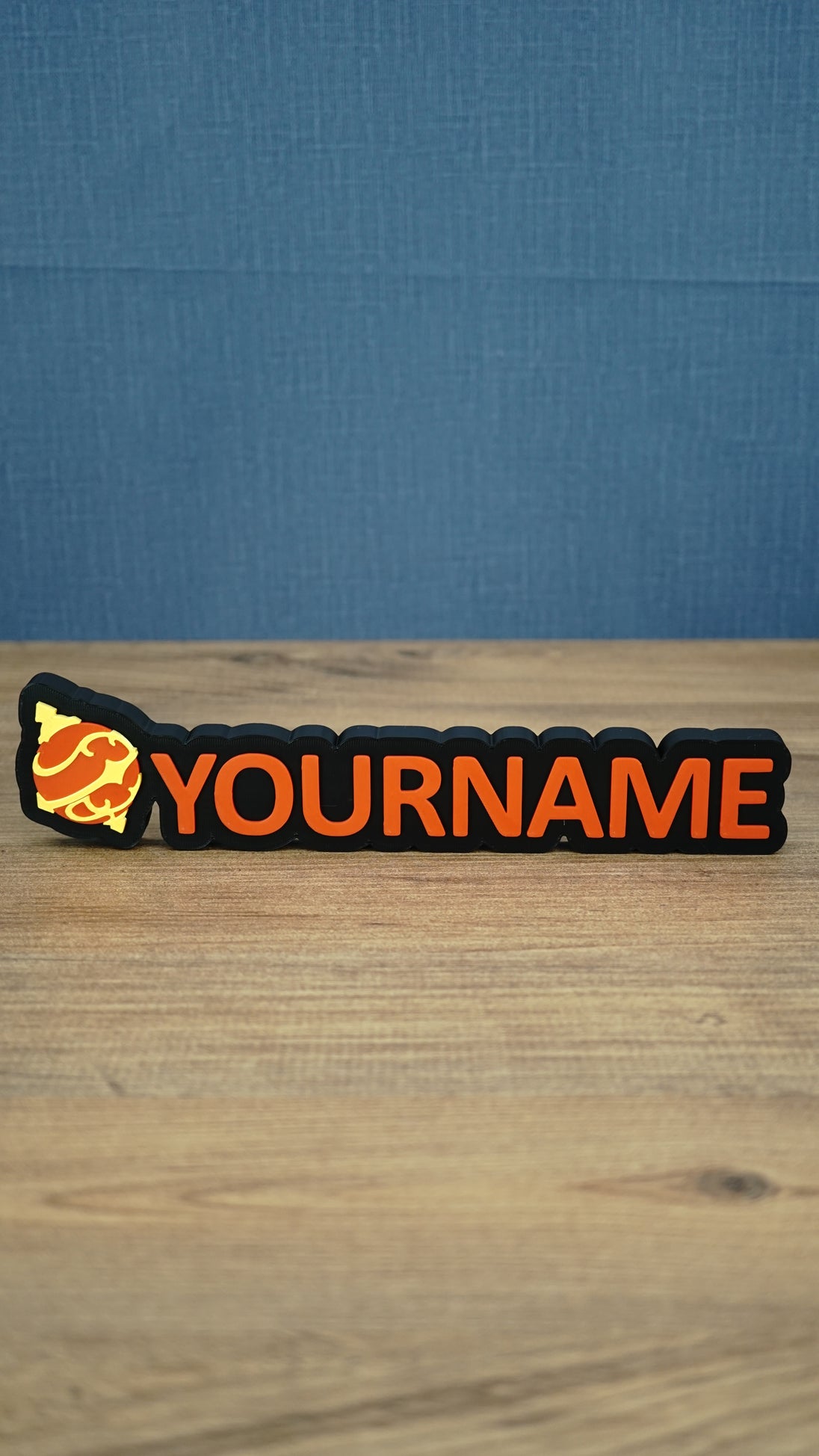 Personalised Palworld Hyper Sphere nameplate in red on a black base, shown front-on on a wooden desk with custom YOURNAME lettering.