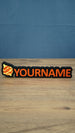 Personalised Palworld Hyper Sphere nameplate in red on a black base, shown front-on on a wooden desk with custom YOURNAME lettering.