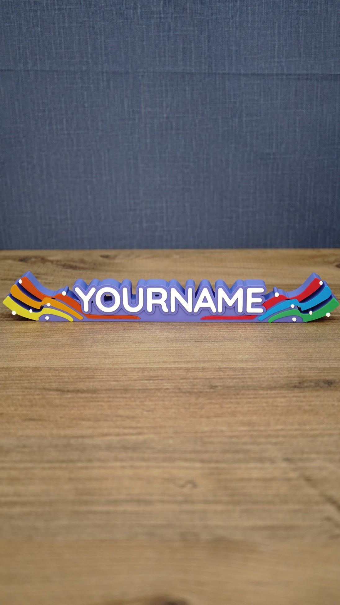 Front view of a personalized Palia Prismatic Pride nameplate with white lettering, a purple base, rainbow flourishes, and small white accents.