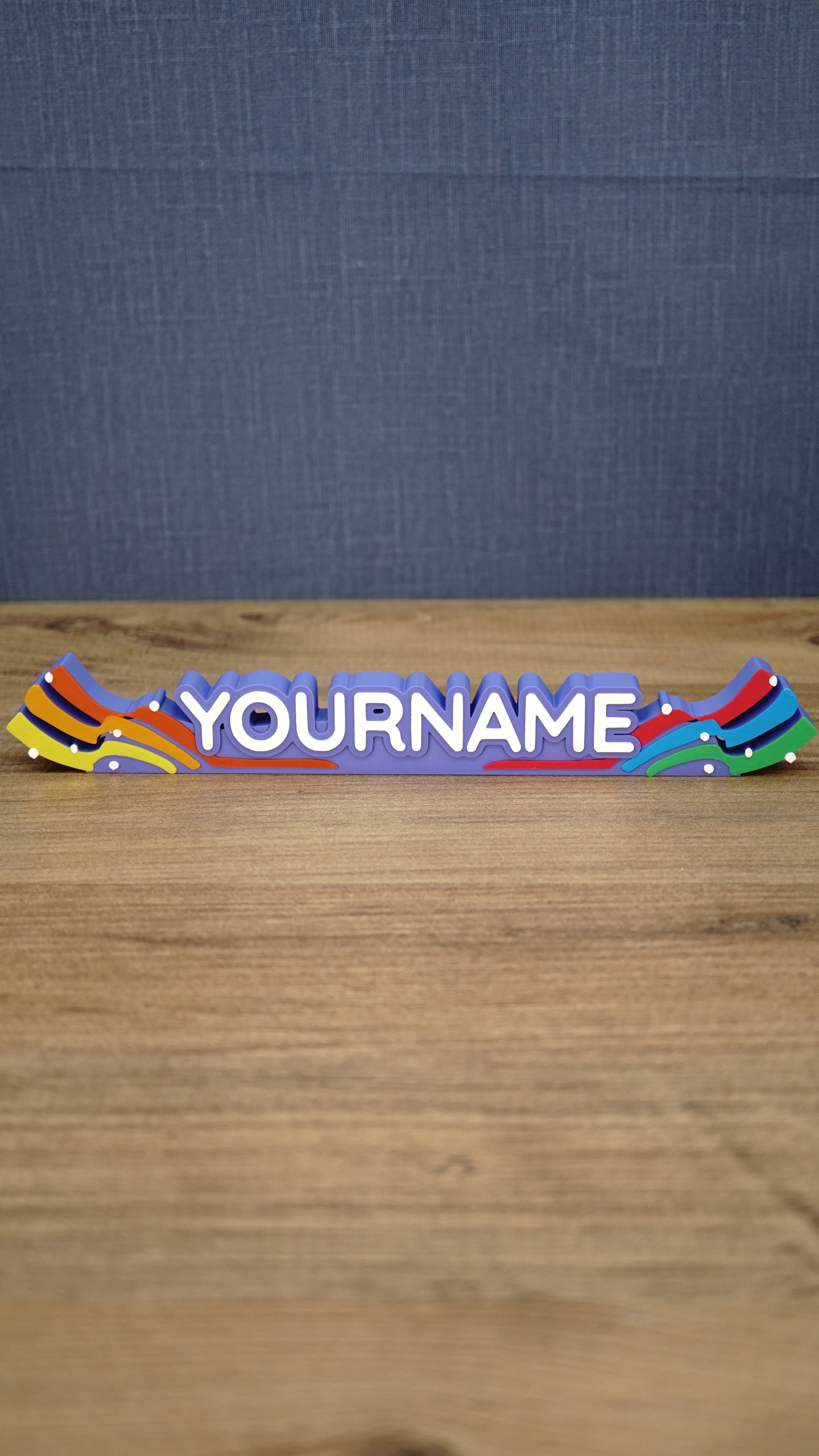 Front view of a personalized Palia Prismatic Pride nameplate with white lettering, a purple base, rainbow flourishes, and small white accents.