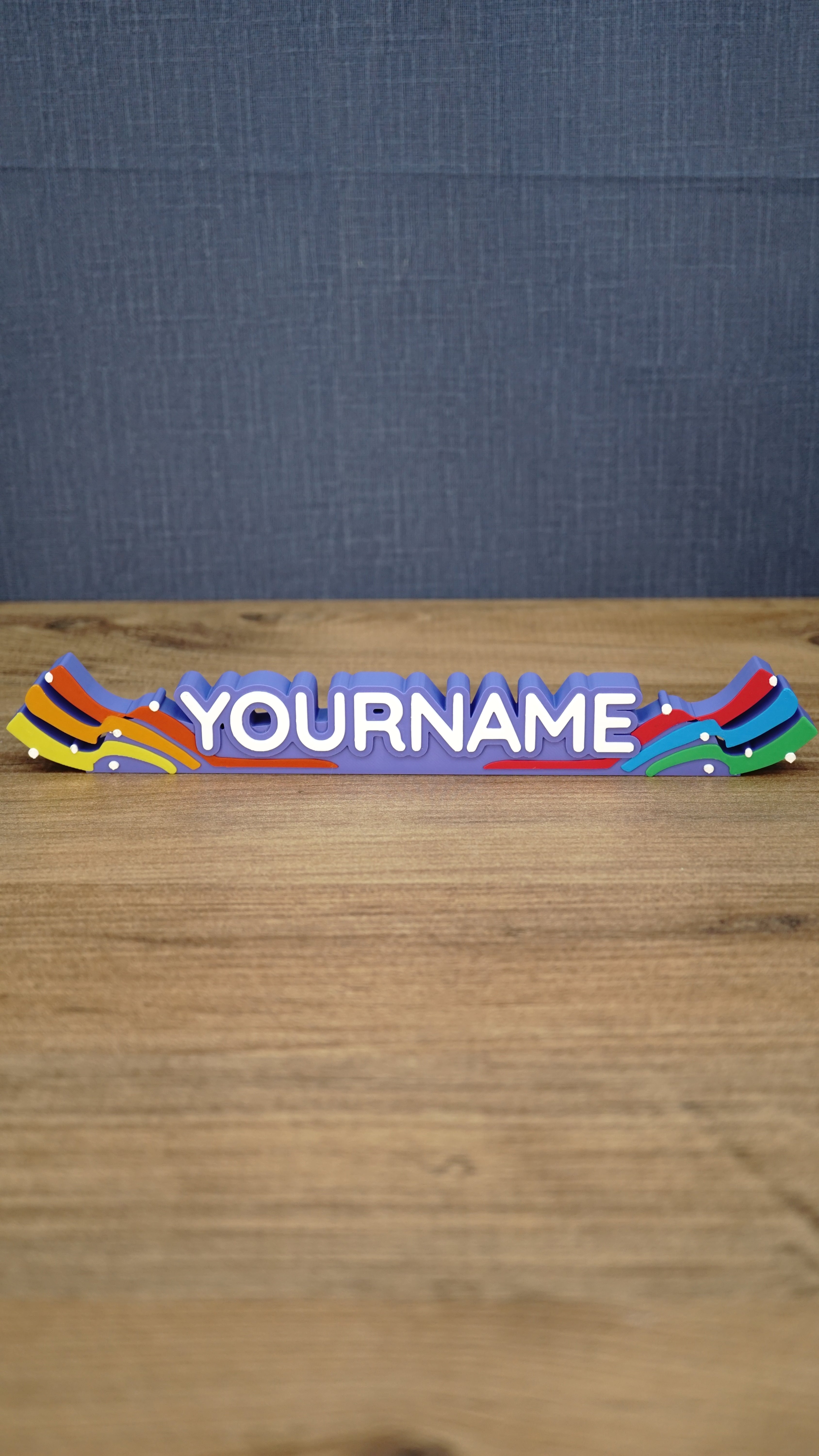 Front view of a personalized Palia Prismatic Pride nameplate with white lettering, a purple base, rainbow flourishes, and small white accents.