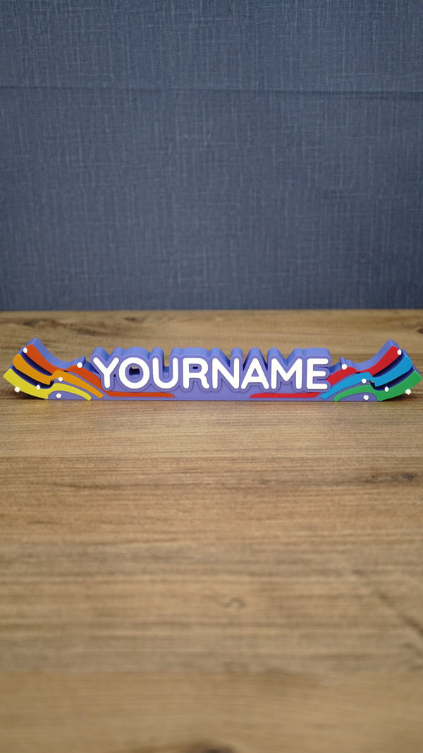 Front view of a personalized Palia Prismatic Pride nameplate with white lettering, a purple base, rainbow flourishes, and small white accents.