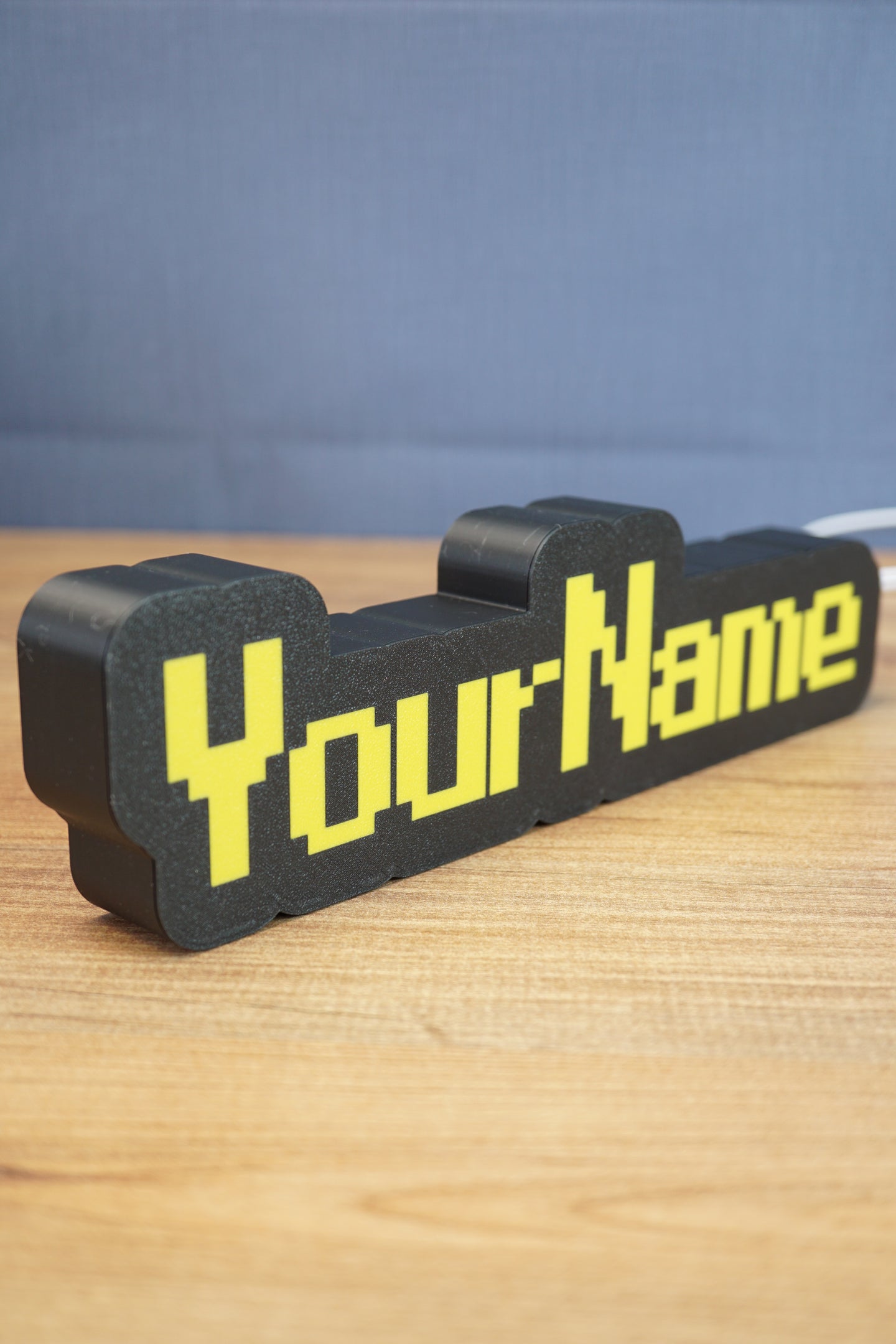Angled view of a personalized YourName LED desk sign featuring RuneScape-style yellow lettering and a bold black frame.