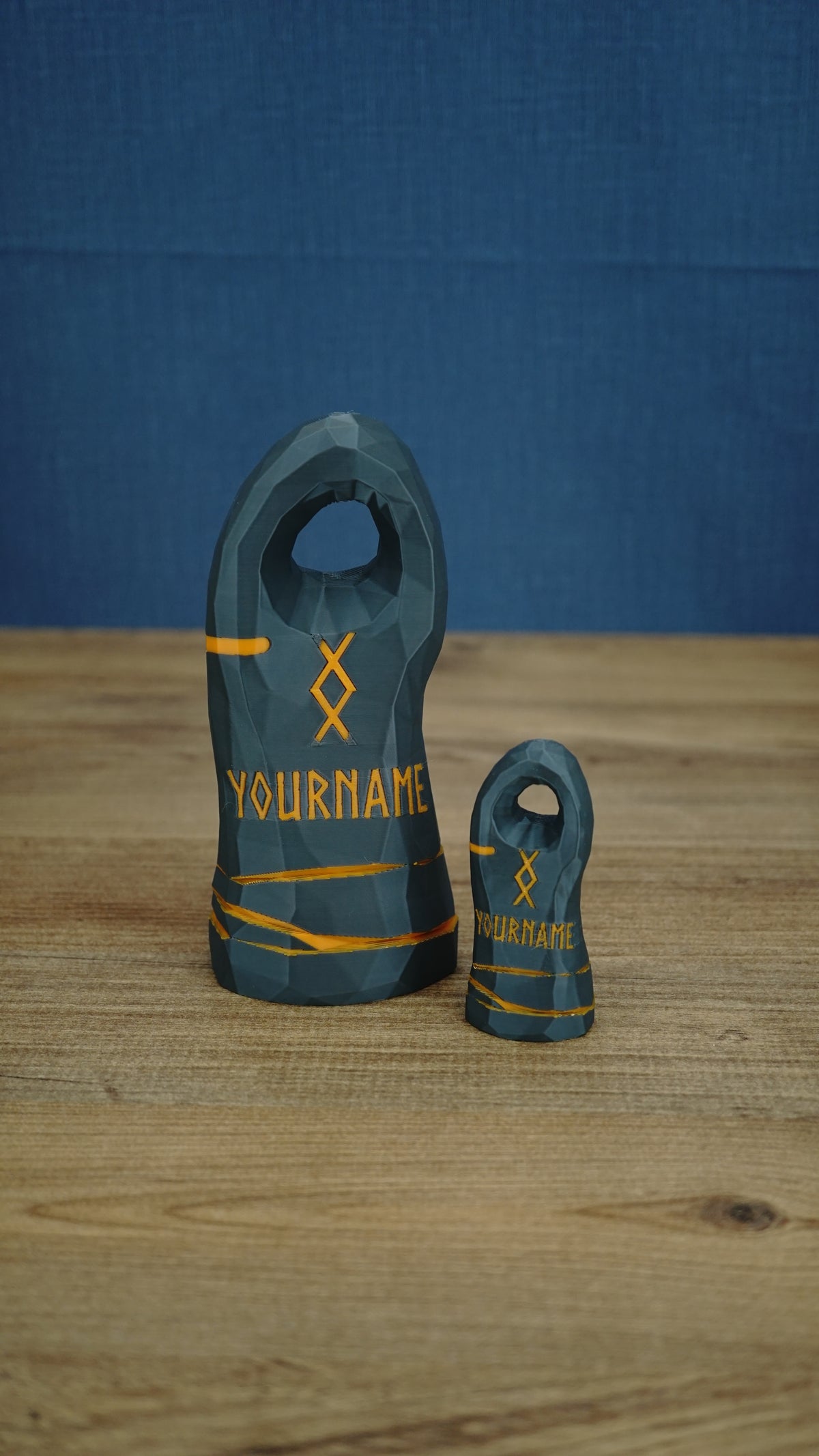 Two dark gray personalized Valheim-inspired tombstones in large and small sizes, with orange rune details and custom name text.