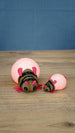 Large and small pink Palia-inspired lantern bug plush figures displayed together on a wooden tabletop.