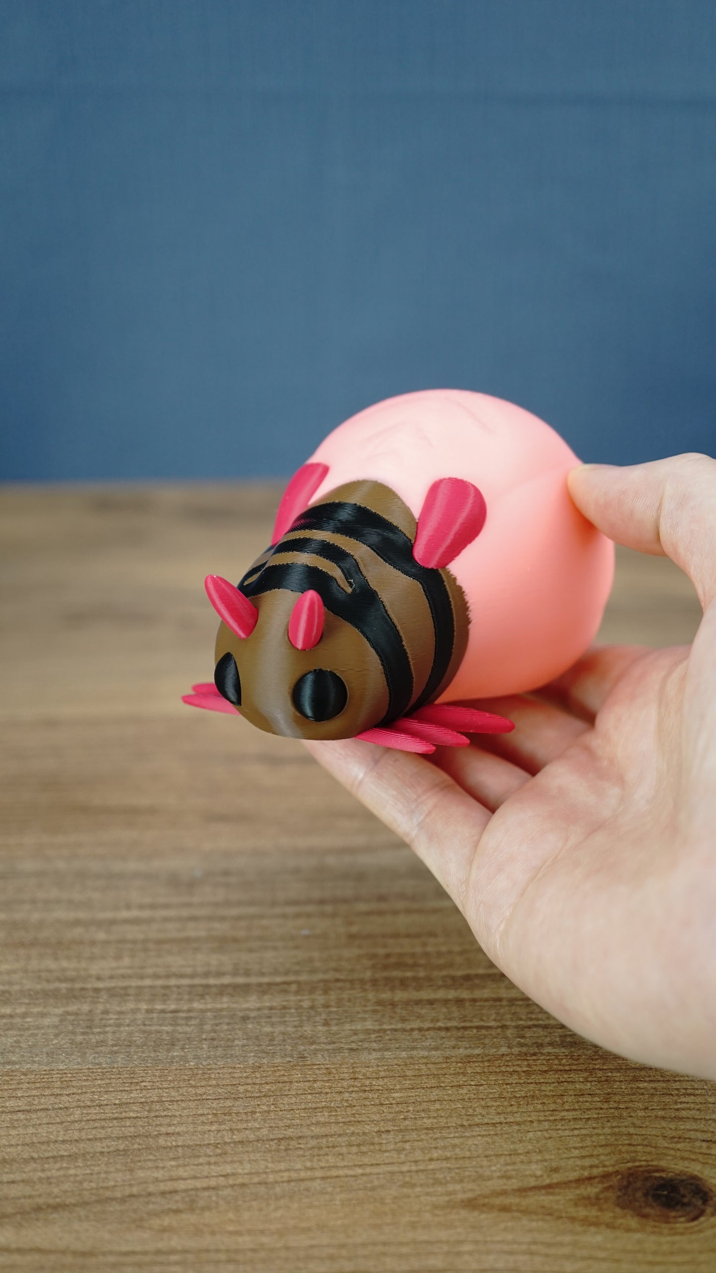 Hand holding a pink Palia-inspired lantern bug plush figure to show its size and shape.