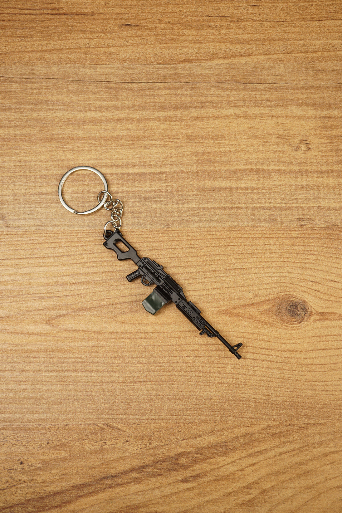 Close-up angled PKM rifle keyring with detailed LMG shape, metal chain and key ring, made for FPS fans and gaming gift collections