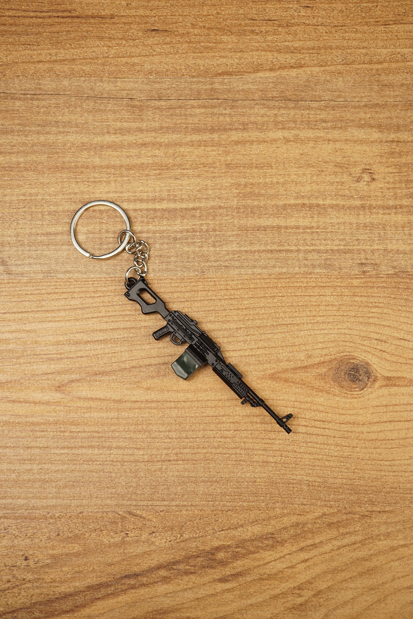 Close-up angled PKM rifle keyring with detailed LMG shape, metal chain and key ring, made for FPS fans and gaming gift collections