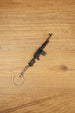 Angled PKM metal rifle keychain on a wooden background, ideal as a tactical shooter accessory, bag charm or gamer collectible