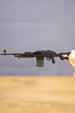 Side view of PKM rifle keyring held between fingers, showing the compact metal LMG design and realistic miniature gamer accessory details

